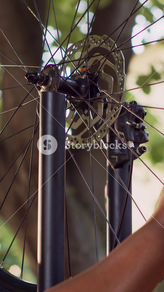 Vertical video Close-up shot of energetic interracial couple outside safely placing wheel on bicycle body. Detailed view of bike tire