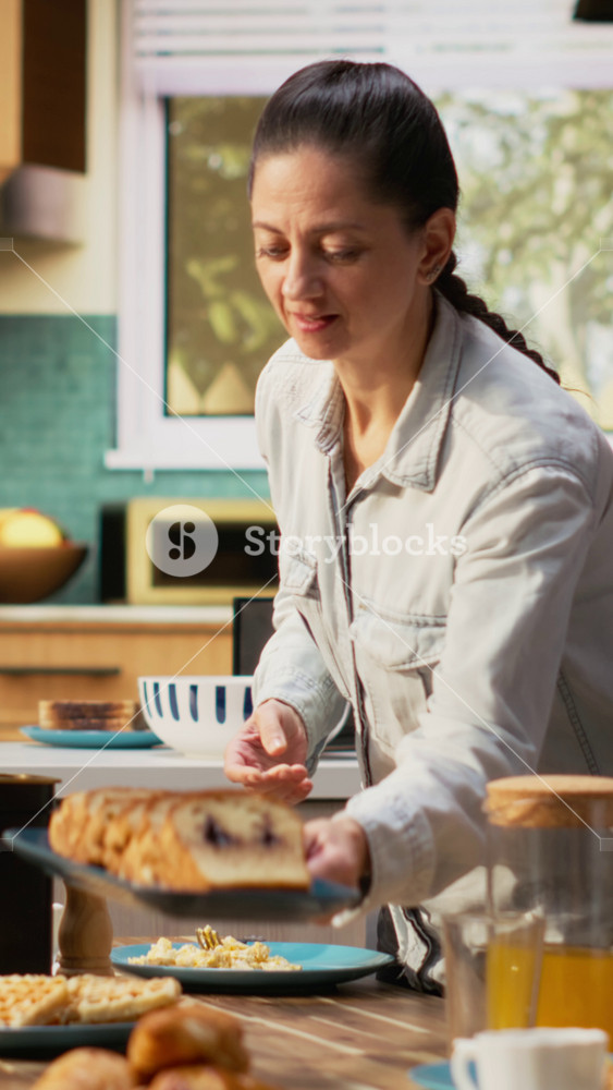 Vertical Video Family with a pre-teen girl serving breakfast together in a bright kitchen, parents pour orange juice and daughter enjoys