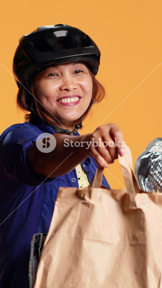Close up shot of courier arriving to customer address, taking meal bag out of thermic backpack. Happy BIPOC bike rider delivering lunch to