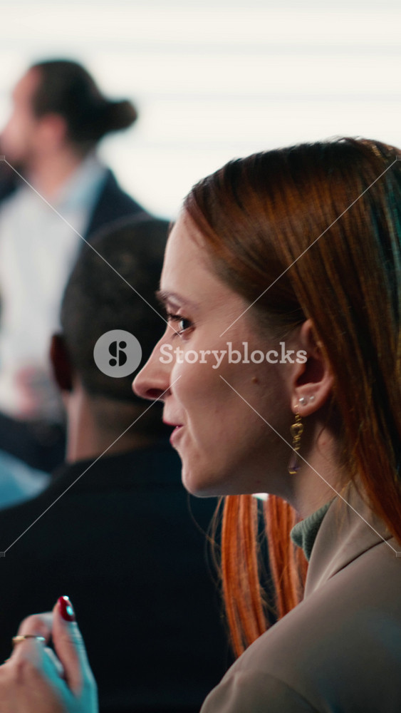 Vertical Video Young adult businesswoman attending international conference with male speaker on stage delivering a speech during business