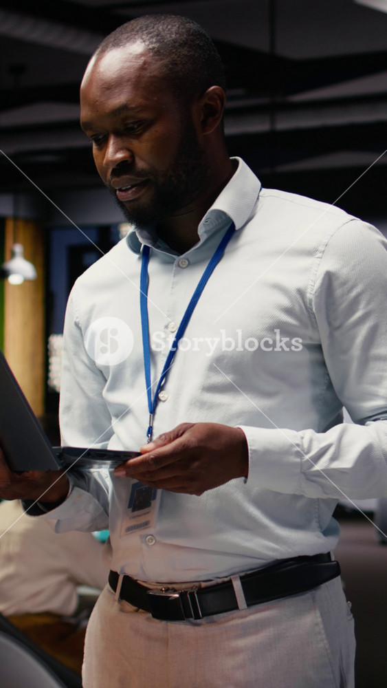 Vertical Video Portrait of black businessman in office managing schedules on laptop, organizing calendar appointments and meetings. Male