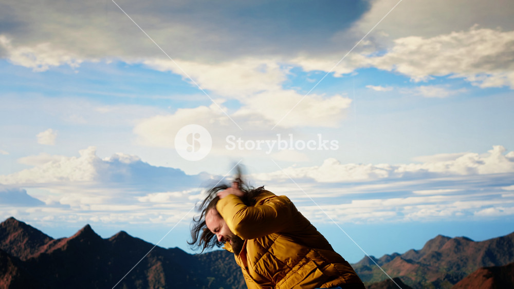 Clumsy adventurer finds himself at the mercy of the wind struggling to keep balance, falling off of a mountain top. The cold weather proves