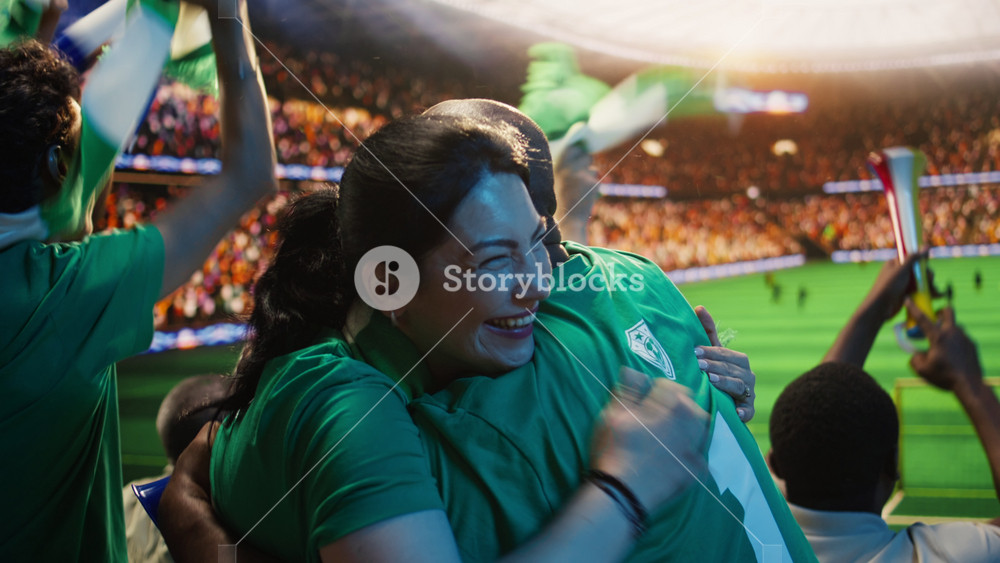 Delighted football supporters hugging in stadium stands after goal during soccer match. Cheerful man and woman embracing during happy match
