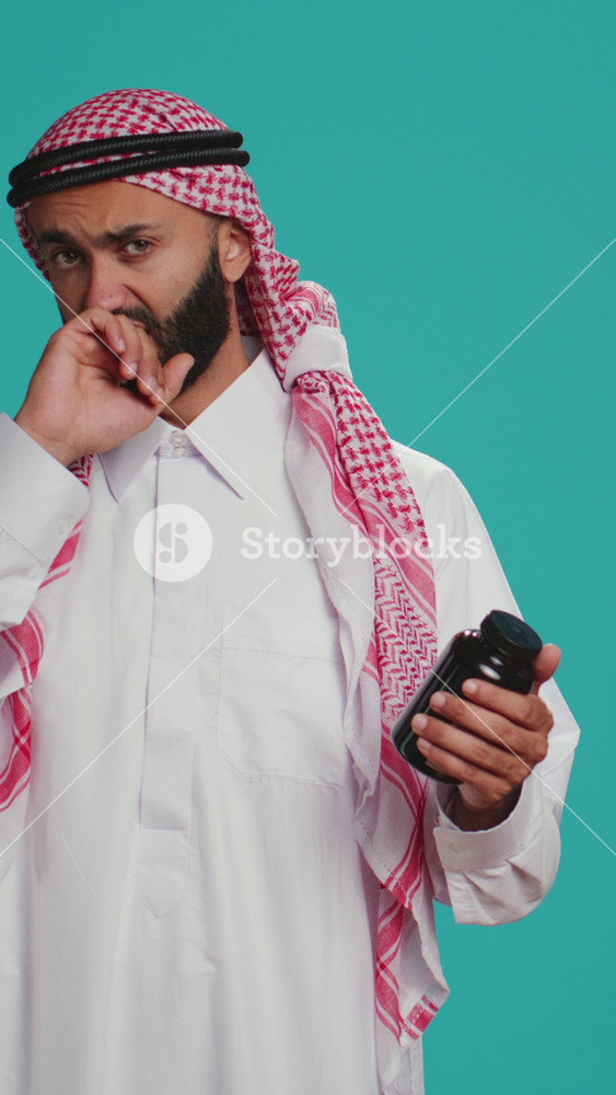Vertical video Muslim adult looks at jar of pills on camera, preparing to take painkillers or vitamins from bottle of medicine. Young person