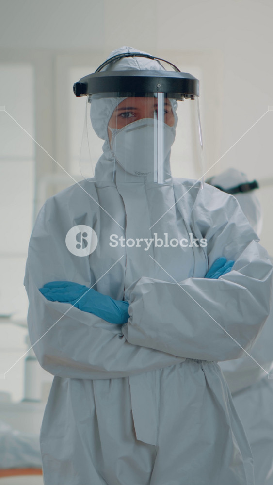 Vertical video: Portrait of caucasian dentist prepared for dental surgery at oral clinic, wearing protection suit with mask, face shield