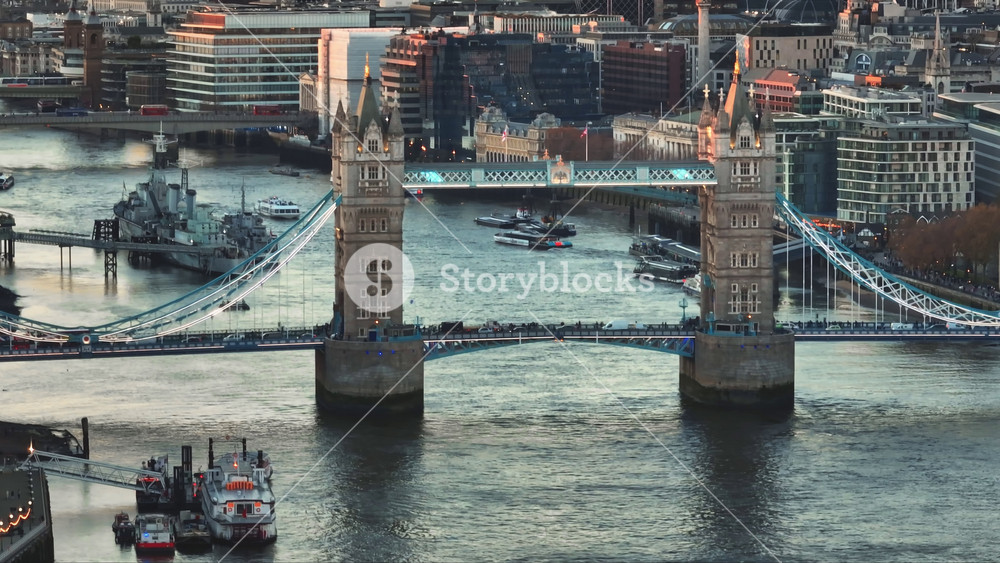 United Kingdom, London: Aerial view of Tower Bridge at sunset over River Thames with boats sailing and HMS Belfast docked, in London, United