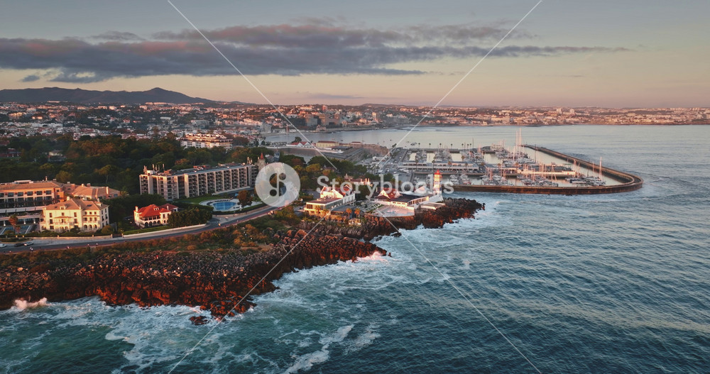 Portugal, Lisbon: Cascais coastal town with Santa Marta Lighthouse and marina bathed in golden light during colorful bright sunset, Iberian