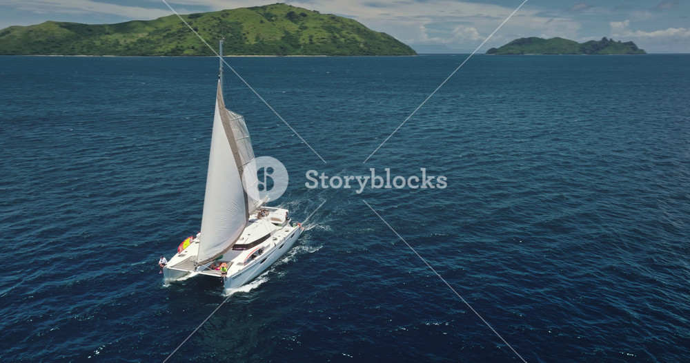Catamaran sailing in the ocean near Kuata island, Fiji, aerial drone footage capturing the vastness of the sea and the beauty of the