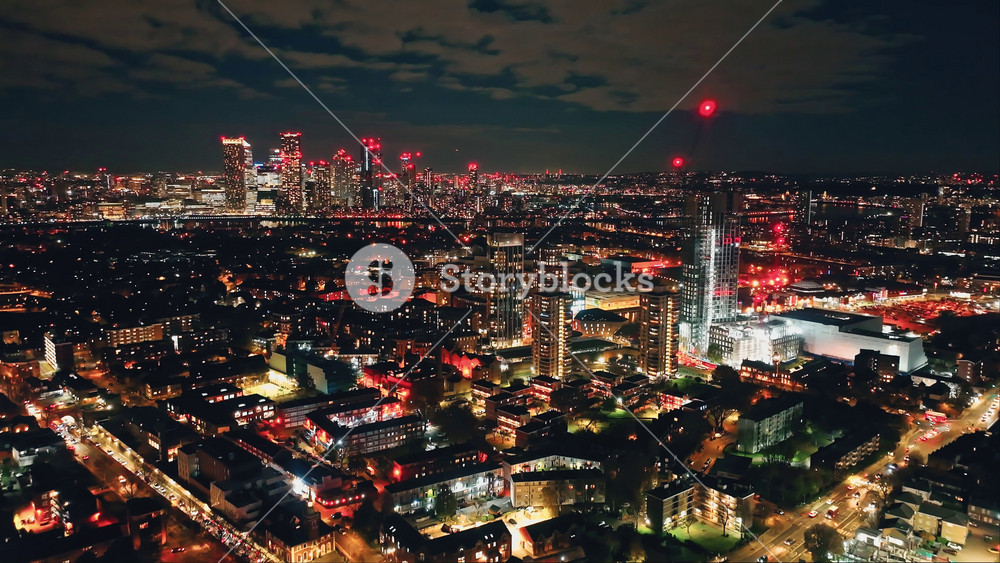 Breathtaking aerial view of London at night, highlighting the vibrant glow of Canary Wharf amidst a bustling urban landscape filled with