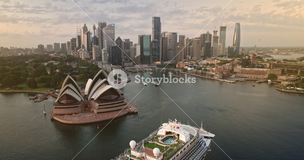 Huge cruise tourist ship and iconic Sydney Opera House city skyline, modern city center skyscrapers and the bustling harbour at sunset