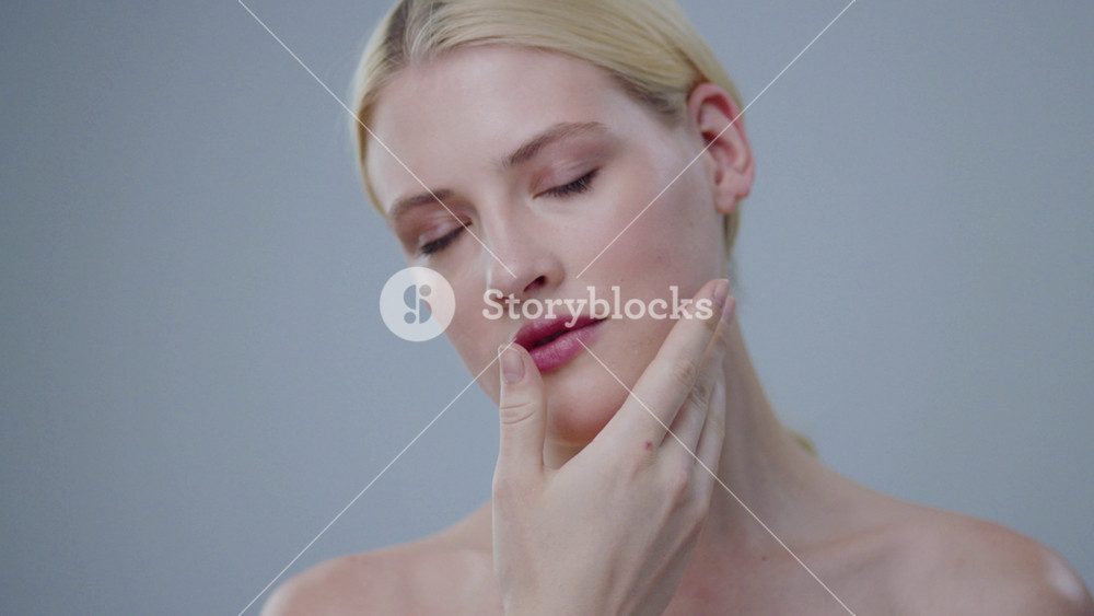 Beauty fashion girl touching her clear fresh face with gentle moves. Portrait of sensual young woman having spa treatment in a salon.