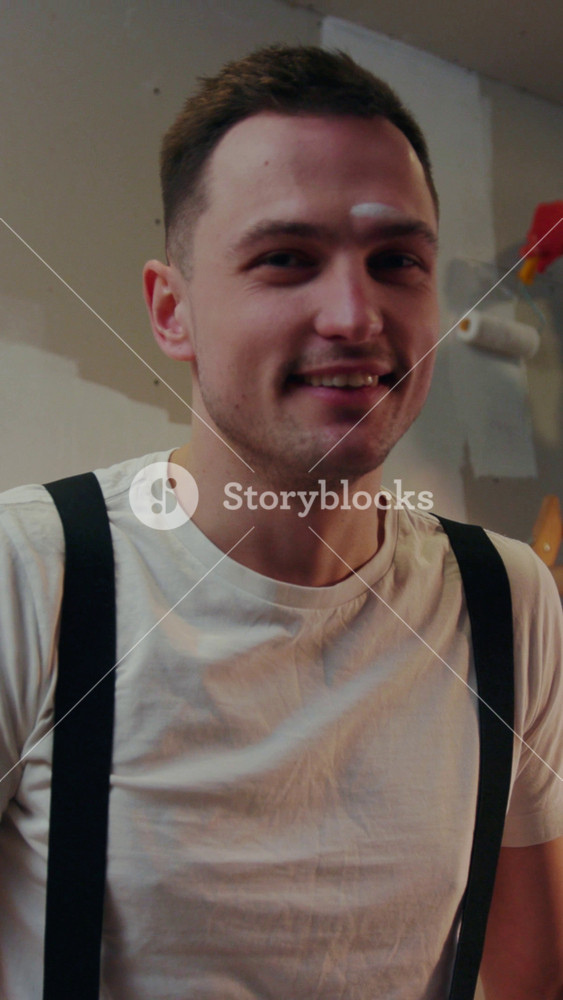 NEW YORK - April 5, 2017: Attractive young repairman looks straight to camera, cheerfully smiles, and wipes out his forehead, cleaning the