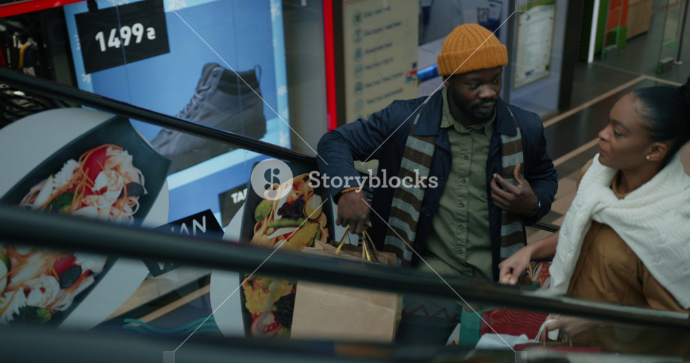 NEW YORK - 19 May 2018: Attractive african american married couple discussing their purchases and Christmas gifts shopping together on black