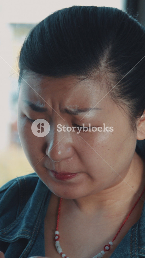 Closeup portrait of mature asian woman riding in public transport tram trolleybus, tapping on touch screen and trying to concentrate