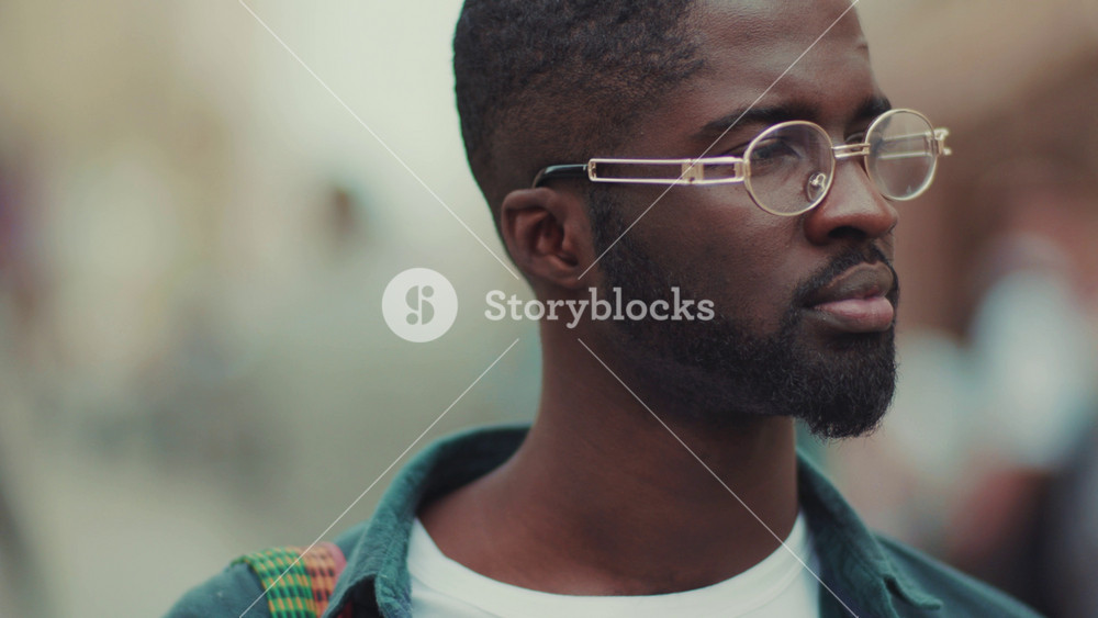 Face young African American with look at camera serious standing in city face outdoor cheerful business fashion attractive portrait close up