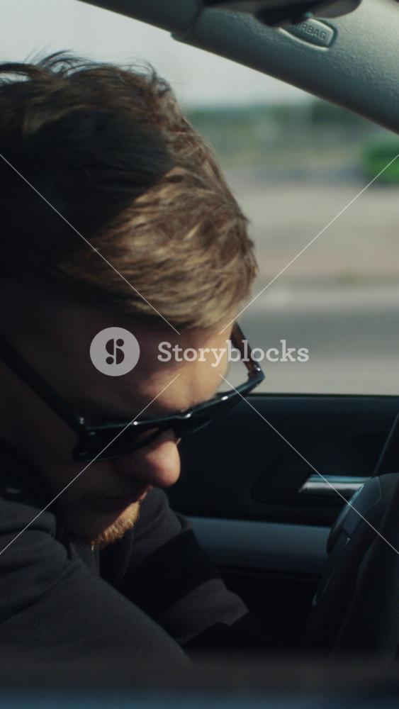 Young bearded man in sunglasses sits in the car, tries to steal it and turn it on without keys, nothing works out, he is caught on the crime