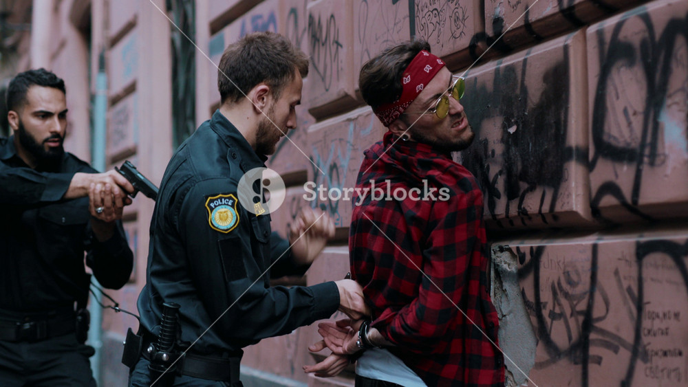 Portrait policeman with pistol arrest robber in handcuffs standing near the car bad guy crime danger dangerous gangster gun illegal law