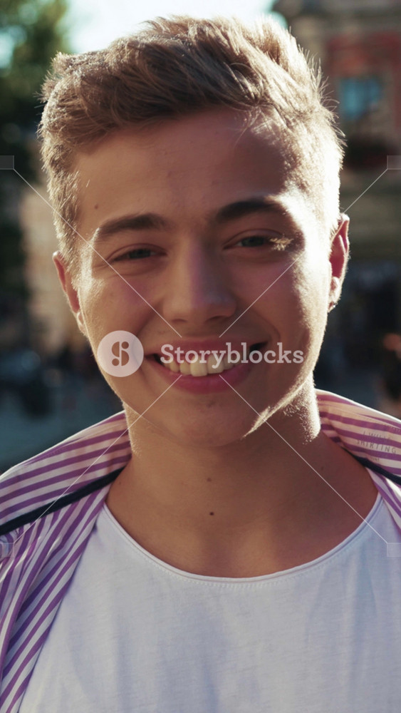 Handsome young man look at camera smile feel happy on street outdoors portrait close up slow motion casual lifestyle city caucasian cheerful