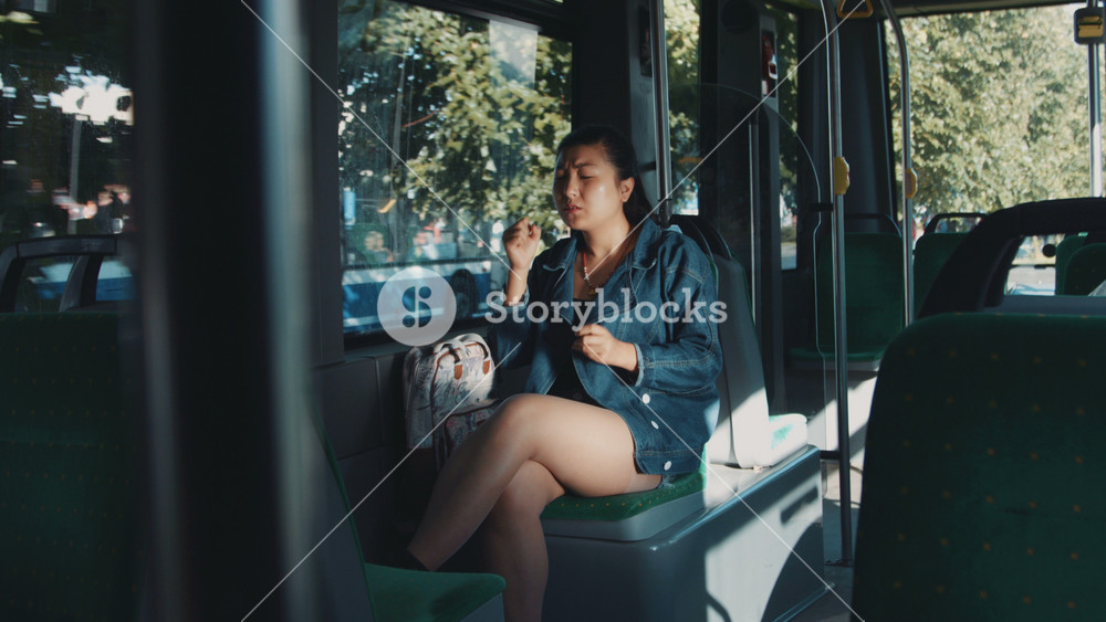 Portrait of mature asian woman riding in public transport tram trolleybus, playing games using smartphone and celebrating virtual victory