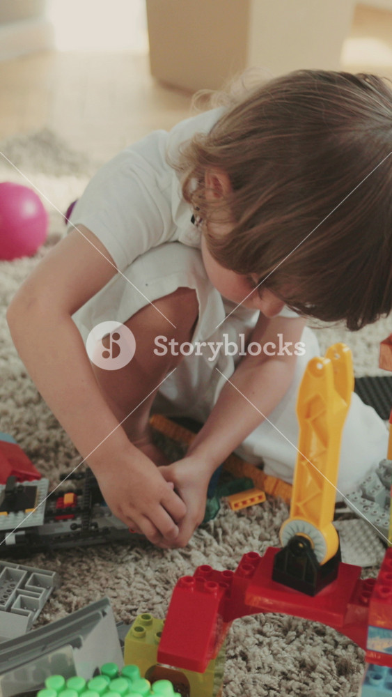 Little cute boy sitting on the floor and enjoying toys at home. The child is a designer. Colored toys, cars, robots, attentive, focused