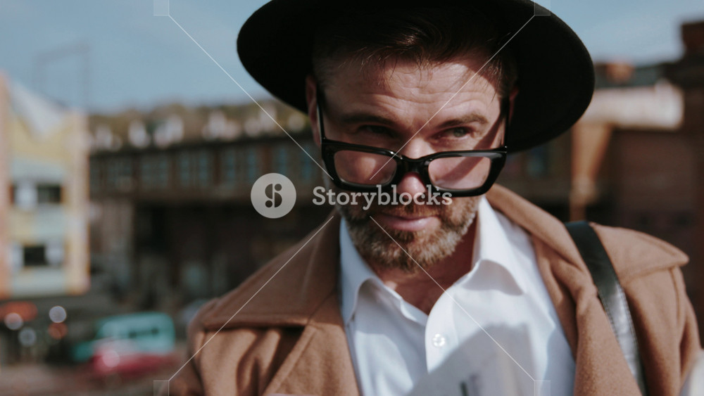 Face close-up of smart detective watching on others up eyes covering his eyes with newspaper stanying on the roof over the criminal city