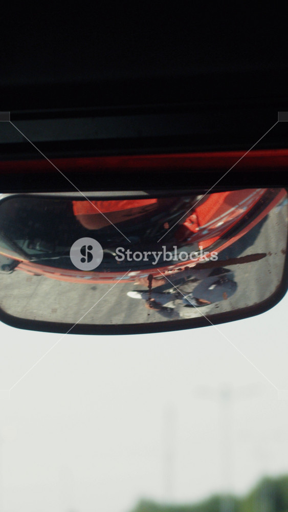 Reflection of the rear-view mirror, strong dangerous armed afro-American thief gets into the stolen truck. The owner of the car lays on the
