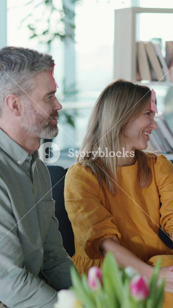 Affectionate happy family of parents and daughter playing sticker game together quessing names having fun in living room. Entertainment home