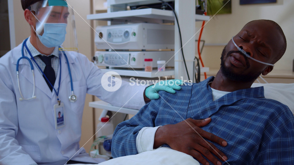 Caucasian doctor treating very sick african patient at hospital room. Therapist prescribing medication tablets for infected unhealthy man