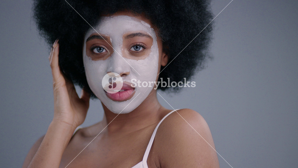 Portrait of gorgeous african girl with a purifying mask winking and flirting on camera. Amazing black female model isolated on dark