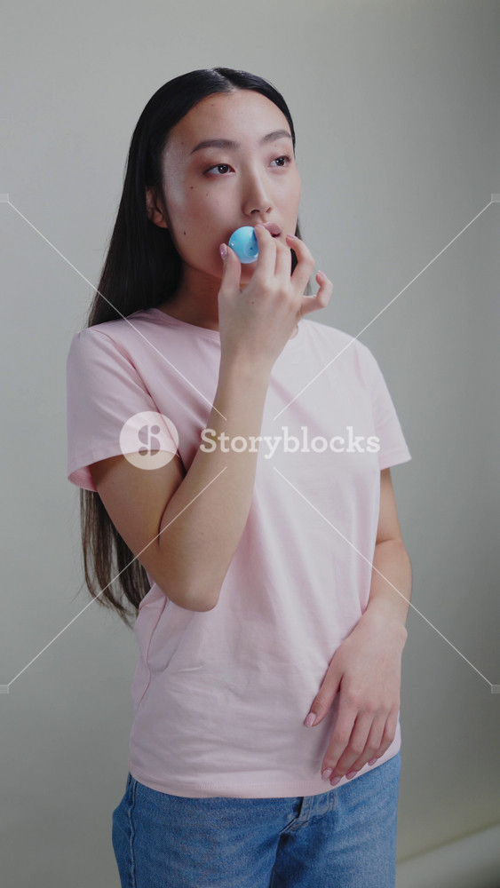 Vertical portrait of asian japanese beautiful girl doing korean skincazre routine applying face cream under eyes. Beauty treatment. Cosmetic