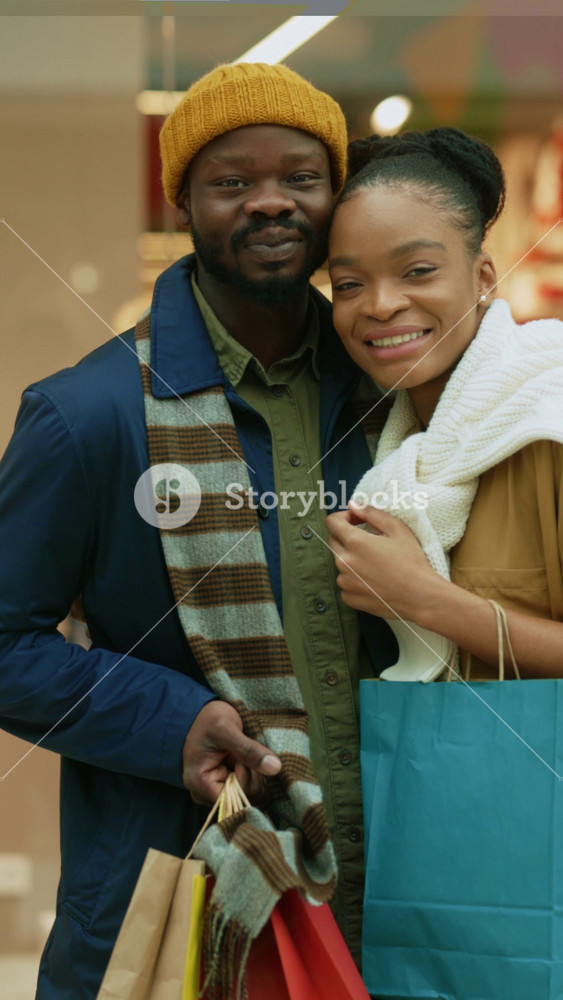 Indoor couple portrait of affectionate happy man and woman hugging together standing near ckothes store shopping in mall together for