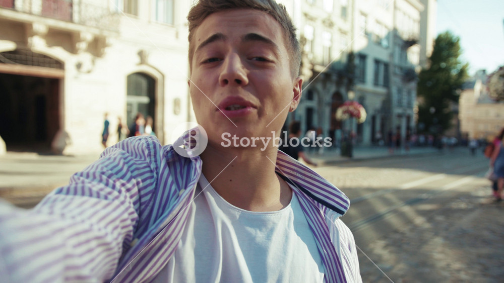 Portrait attractive young man look hold camera smile talk speak feel happy on street outdoors boy close up slow motion casual lifestyle city