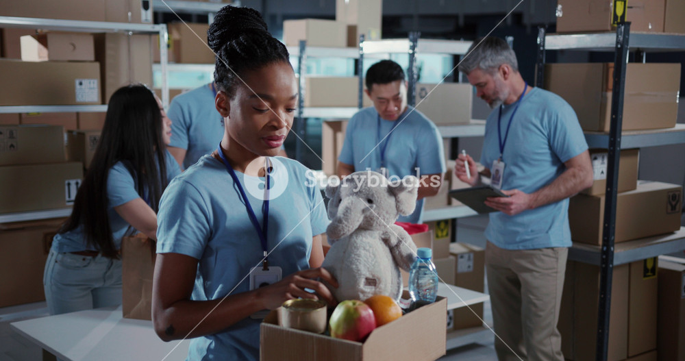 Portrait of african volunteer woman packing box for poor children coworking with colleagues inside workshop. Charity organisations. Free