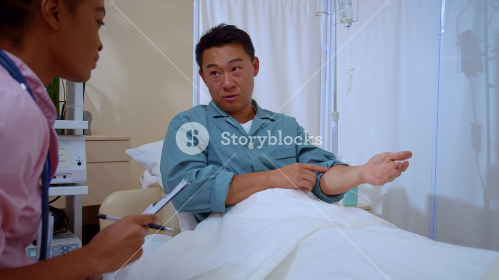 Asian adult patient talking to female nurse doctor writing sickness symptoms disease medical history communicating during doctor checkup at