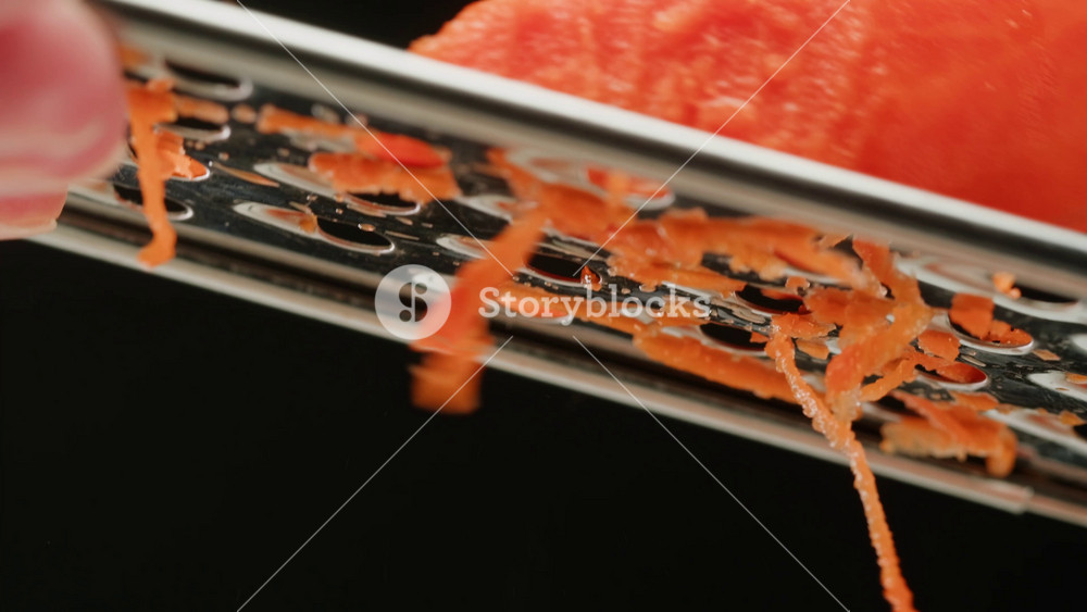 Carrot macro, Woman hands with a grater grate carrots on the wooden board, chef cooking polish potato pancakes in the kitchen. Healthy