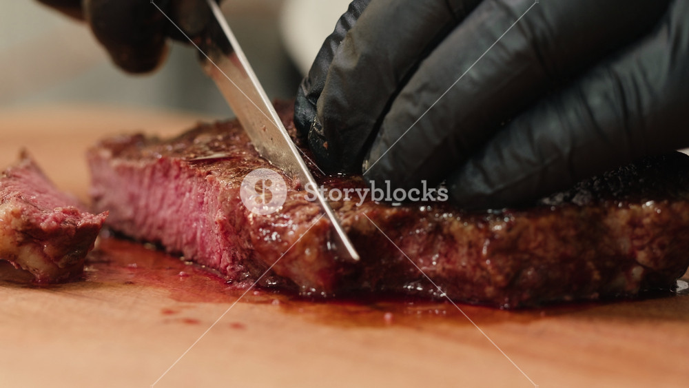 Beef angus steak in restaurant, close up Pieces of hot ribeye steak served on the wooden board. Medium steak slices with blood, salt and