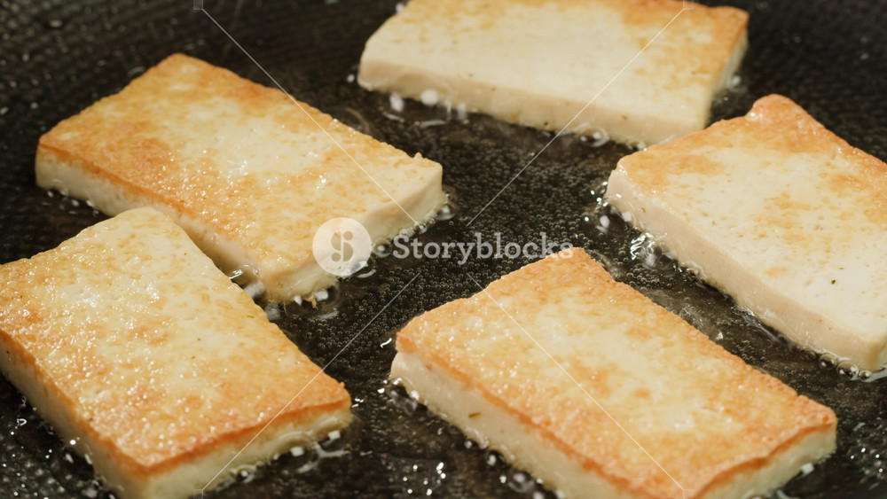 Fried tofu with sesame seeds and spices on cast iron pan, cooking japanese salad. Healthy ingredient for cooking vegan vegetarian diet food