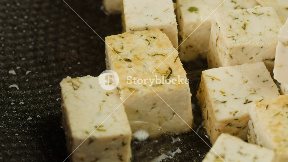 Fried tofu with sesame seeds and spices on cast iron pan, cooking japanese salad. Healthy ingredient for cooking vegan vegetarian diet food