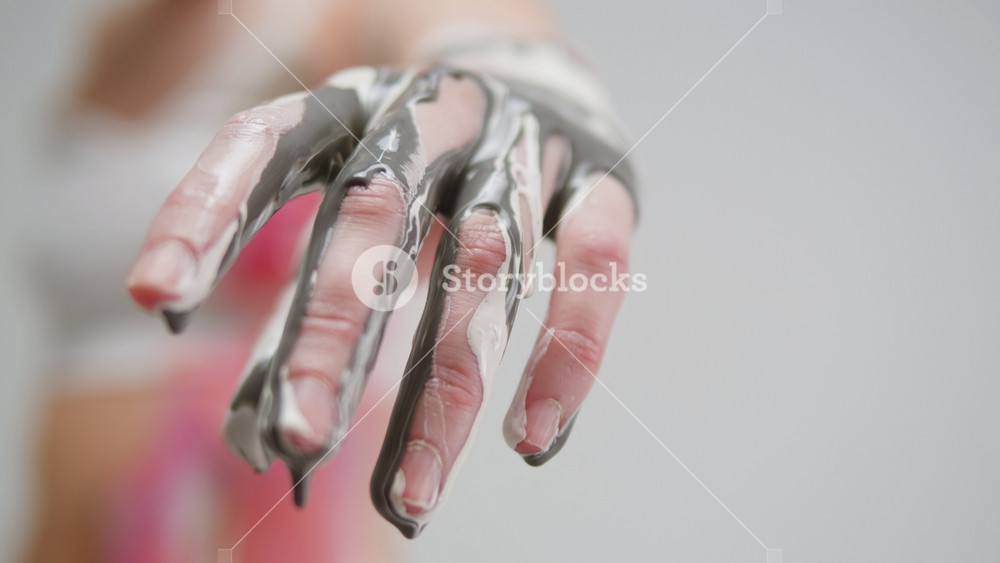 Colourful paint flowing over woman hand fingers close-up. Body art therapy with many various of paints. Painting on human body.