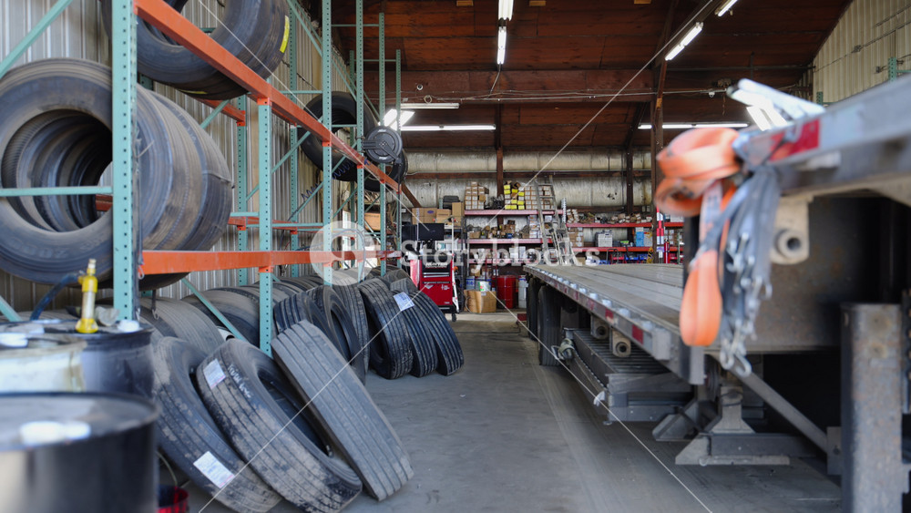 The Step Deck trailer under the repair at the repair shop, Various devices in the repair shop. Semi truck maintenance services. Wide rear