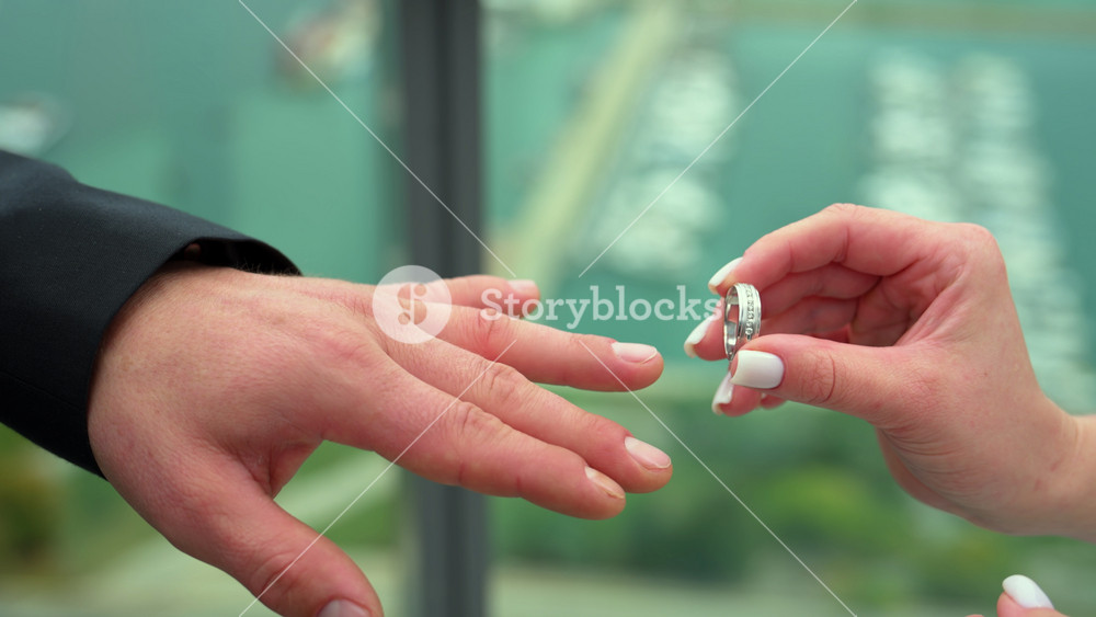 Close-up of a bride placing a wedding ring on the groom finger during the ceremony, capturing a symbolic moment of love, promise, and