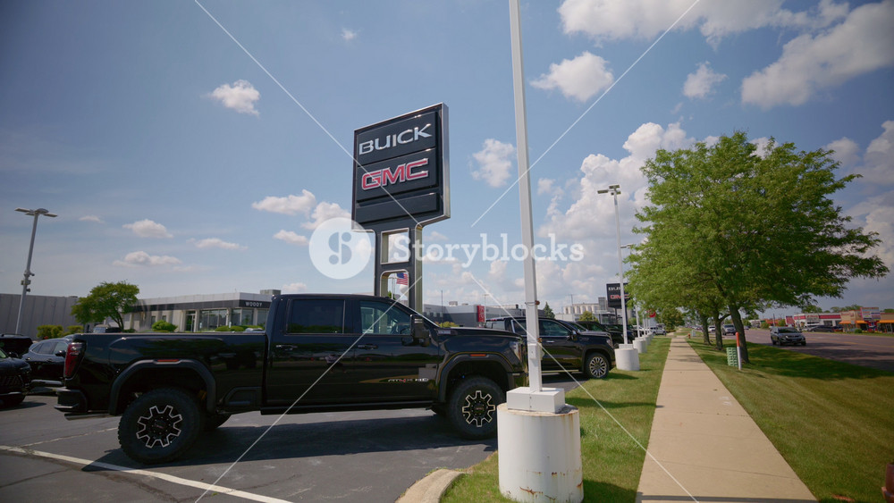 Post with sign of Buick, GMC dealership with cloudy blue sky background. Logo and branding. Bottom up view - June 27, 2025. USA, IL