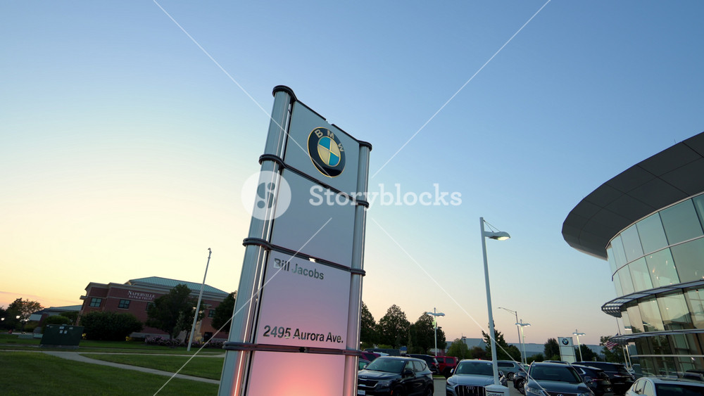 Illuminated sign post of BMW dealership on twilight sky background. The BMW dealership. September 15th, 2025. USA, IL, Naperville