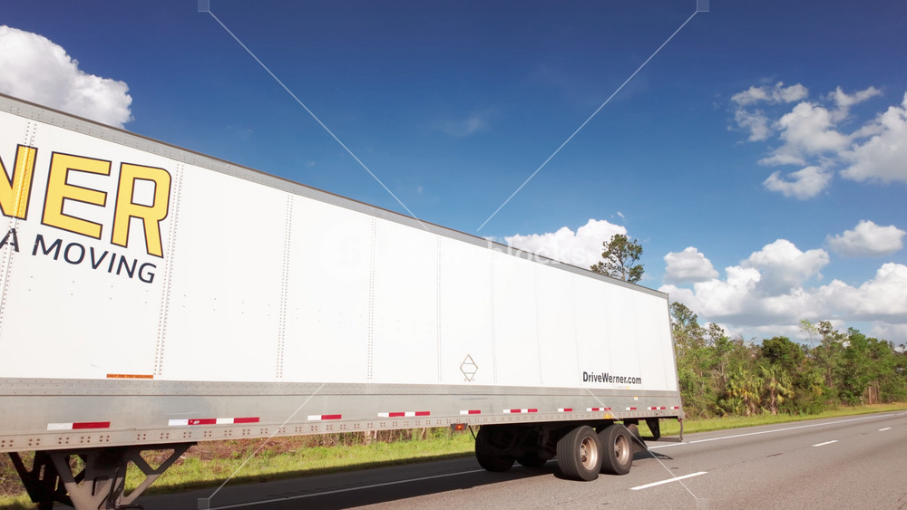 Driving close to the branded semi truck on the spring Florida highway. Wide POV wide shot shot. USA FL Jacksonville 01 Apr 2025