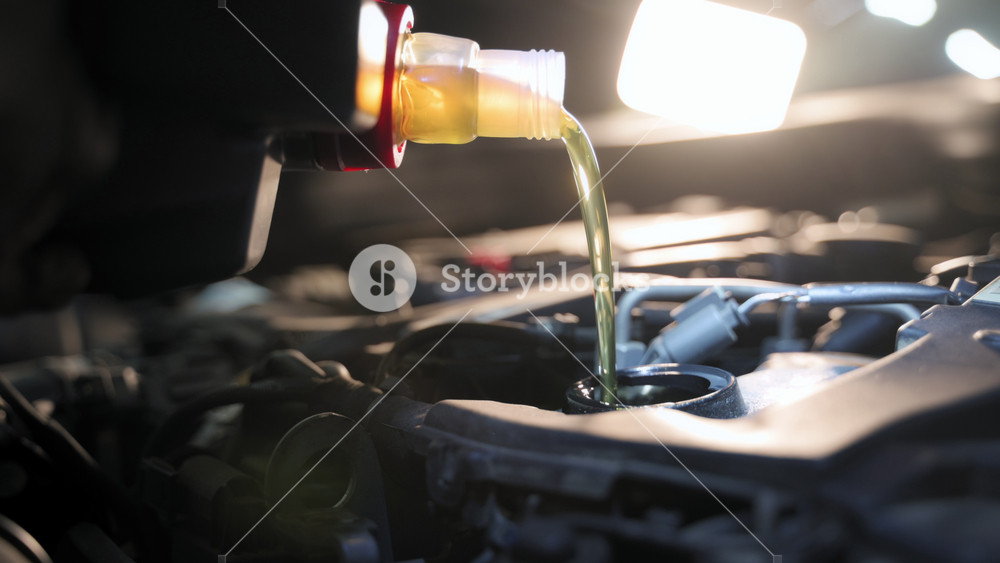 A close-up view of a mechanic changing the car motor oil in a repair shop. During the car inspection or maintenance work