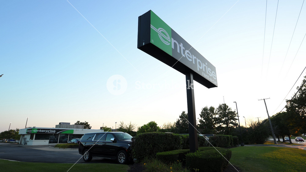 Exterior of Enterprise car Rental services with parked cars on twilight blue sky background. September 15th, 2025. USA, IL, Naperville