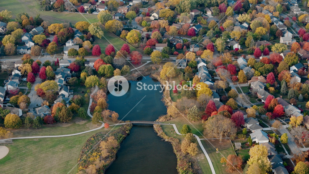 Suburban surrounded by vibrant red and yellow autumn trees. Warm fall colors create a picturesque seasonal neighborhoods, homes, amid