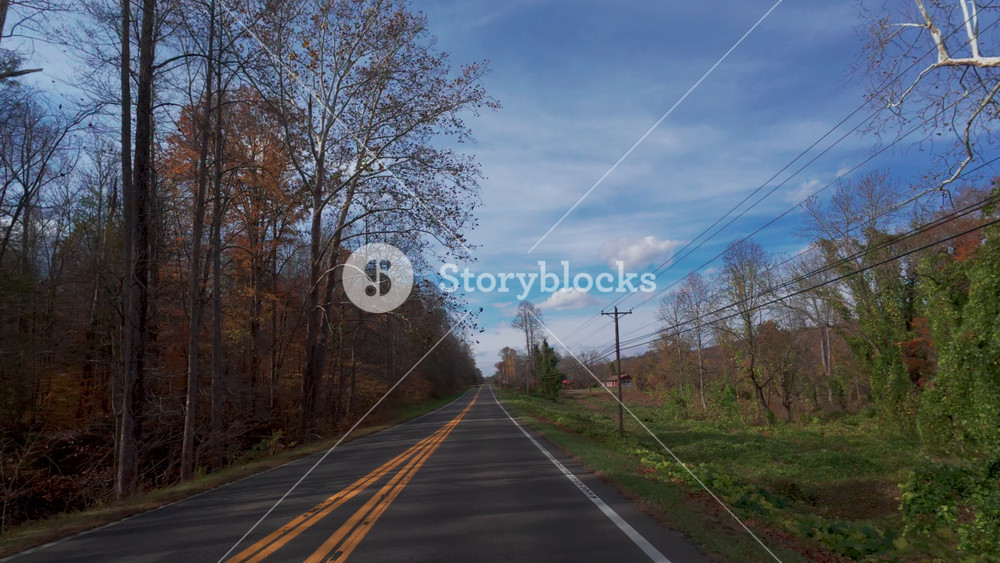 View from a driving car moving along a scenic rural road surrounded by colorful autumn forest and power lines. USA Gatlinburg TN. 2 Nov 2025