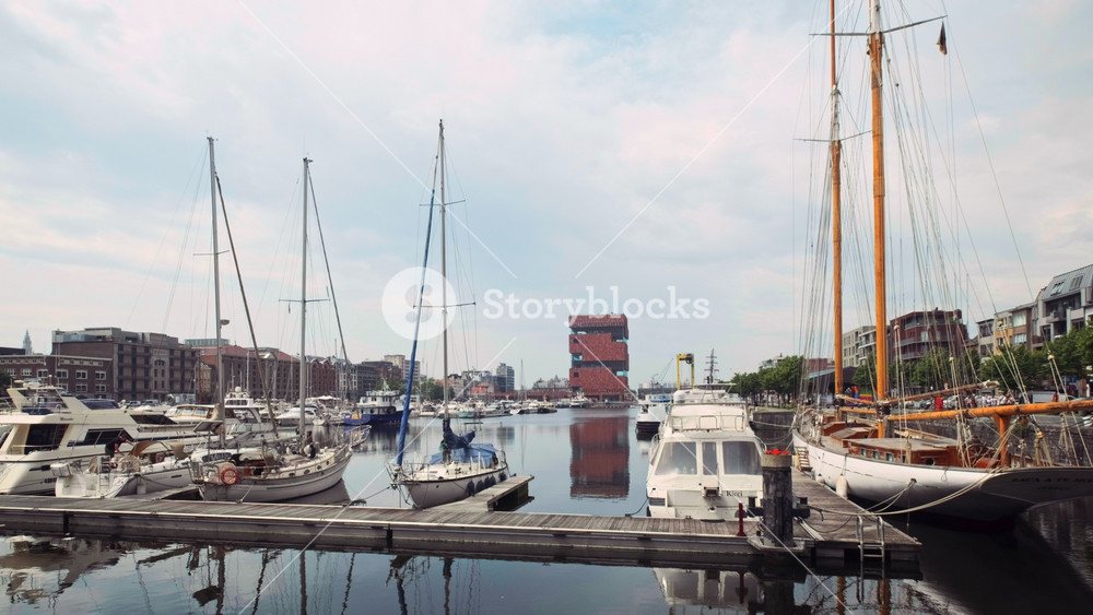 Boats at the oldest harbor district of Antwerp city called Eilandje and MAS Museum aan de Stroom Museum by the River opened in 2011 of postmodern Art Deco architecture