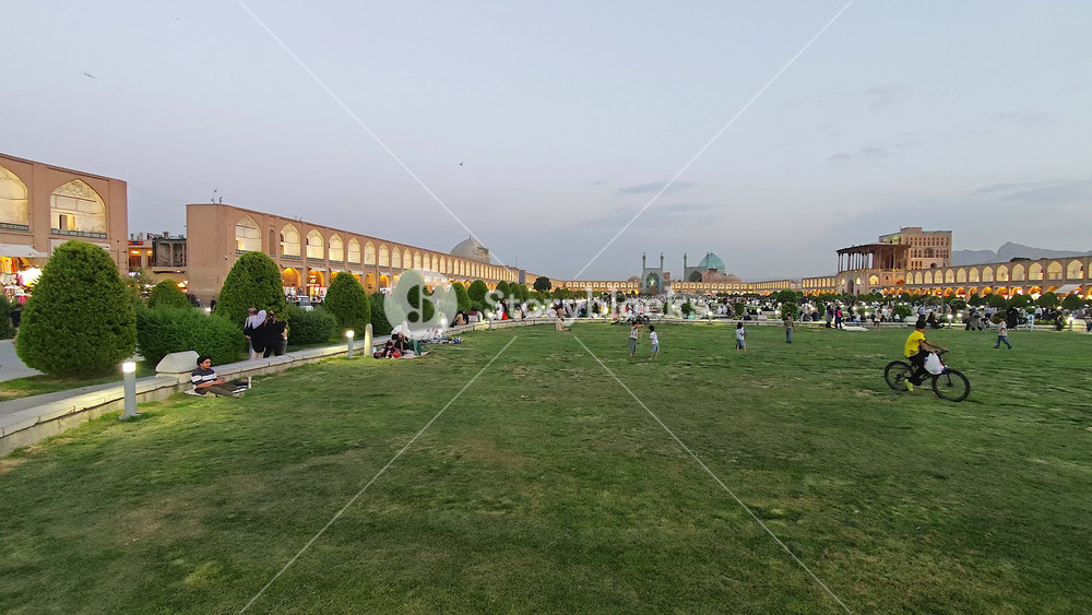 8K Iran Isfahan Naqsh Jahan Square with Shah Abbas Mosque, families, park and daily life. Safavid plaza featuring women, men, gardens, turquoise dome, civic leisure, heritage cityscape.
